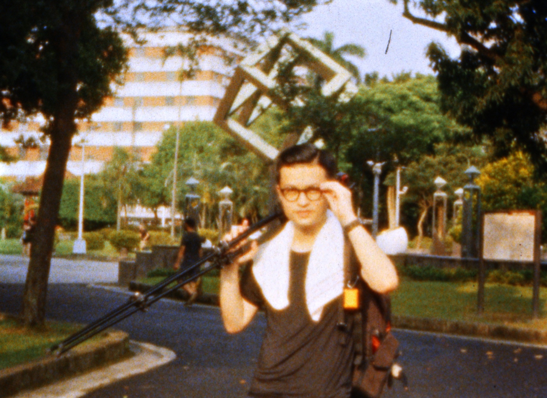 Film director Wei-Heng Kao carrying camera equipment outdoors.